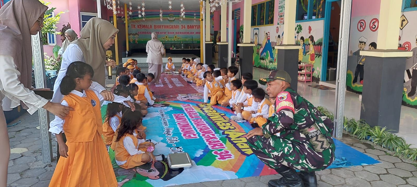 Sertu Joni Setyo Budi Babinsa Kelurahan Pengantigan Koramil 0825/01 Banyuwangi Pendampingan Makan Bergizi Gratis, Hadirkan Senyum di Wajah Ribuan Anak Pelajar